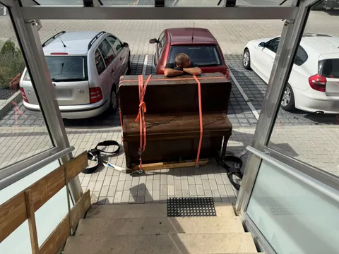 Pianino zajištěné popruhy na přepravní desce před naložením do stěhovacího vozu